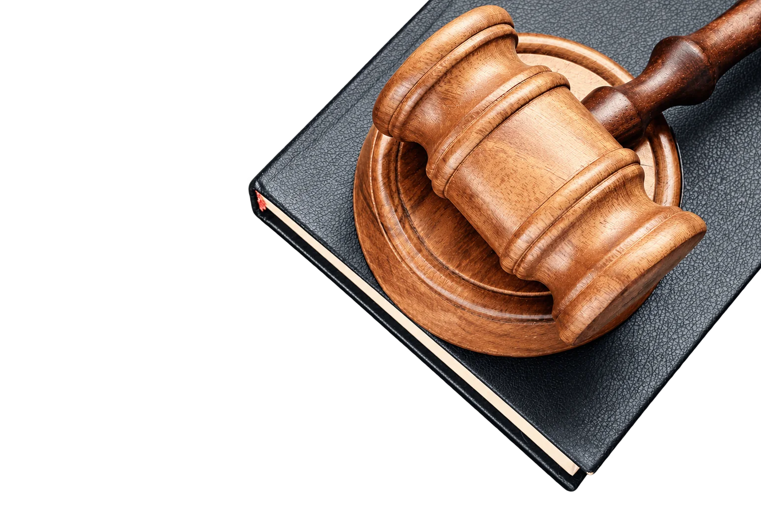 Un marteau de juge en bois et son socle reposent sur un livre à couverture sombre.